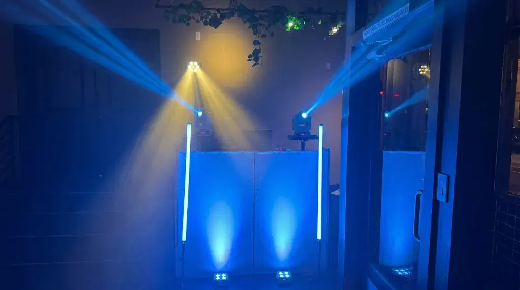 Mobile DJ lighting setup with blue LED tubes, uplights, and yellow and blue moving-head beams at a Pasadena anniversary event