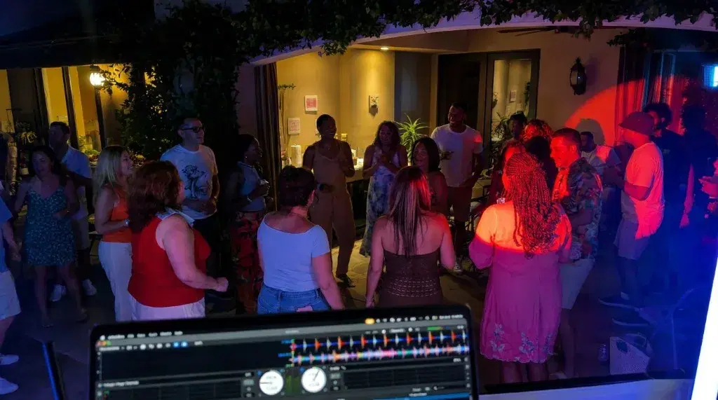 Patio party seen from the DJ booth, with colored lighting across the crowd